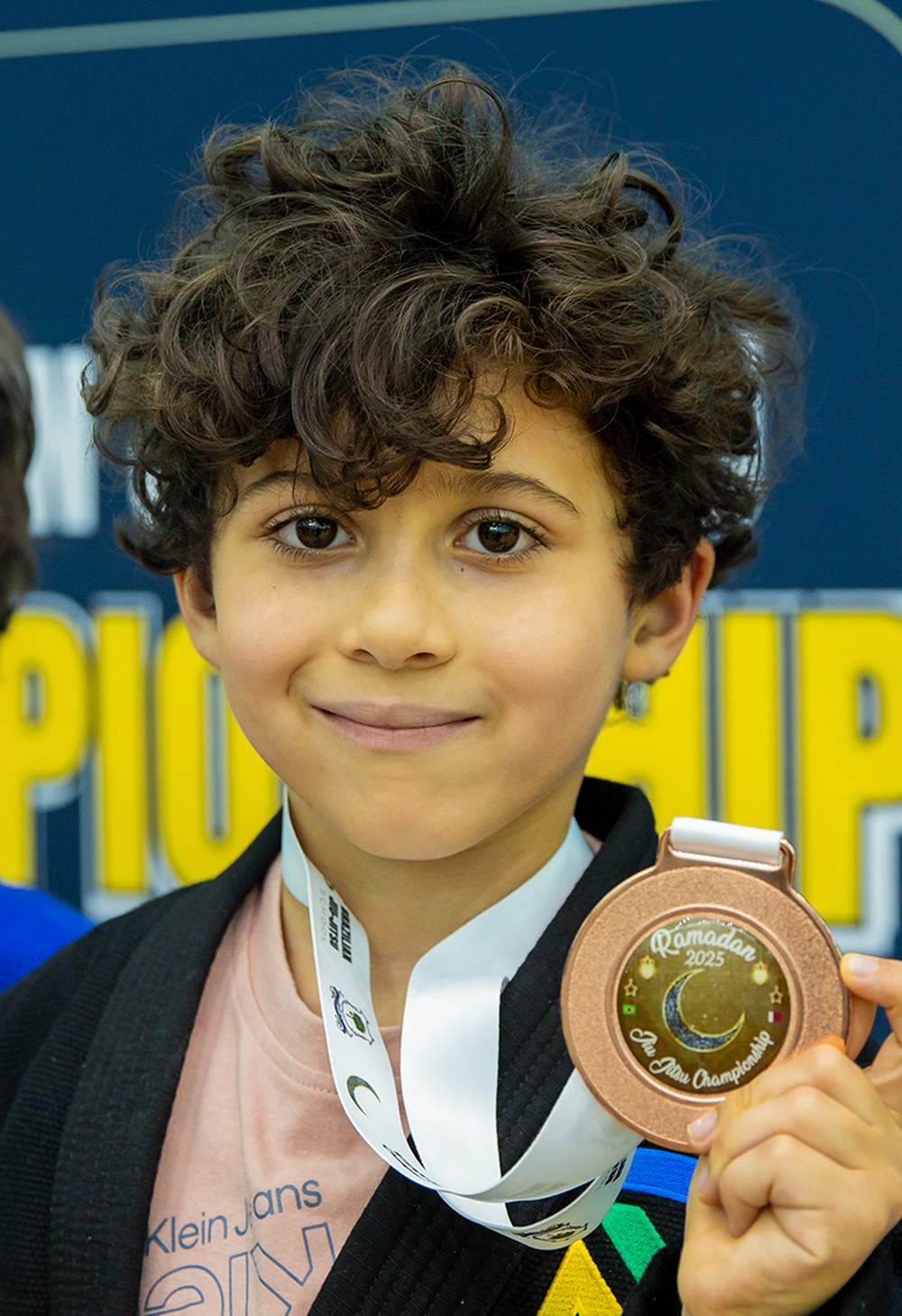 Student holding a Ramadan Jiu Jitsu Championship medal